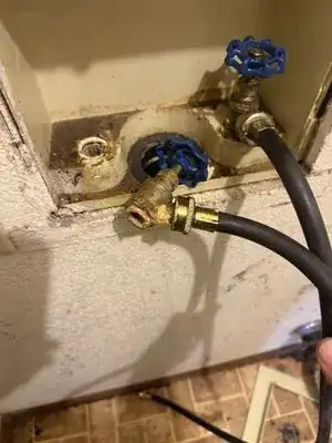Old corroded washer hookup valves and hoses in a laundry wall box before repair