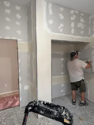 Drywall seams being taped and mudded in a home alcove