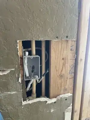 Wall opened up to reach an electrical box and wiring for repair