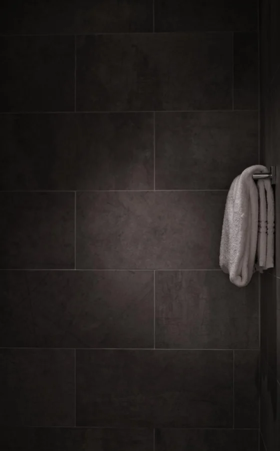 Bathroom wall finished in large-format dark tile with a towel hook