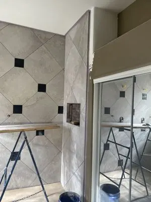 Diagonal shower wall tile being installed during the remodel
